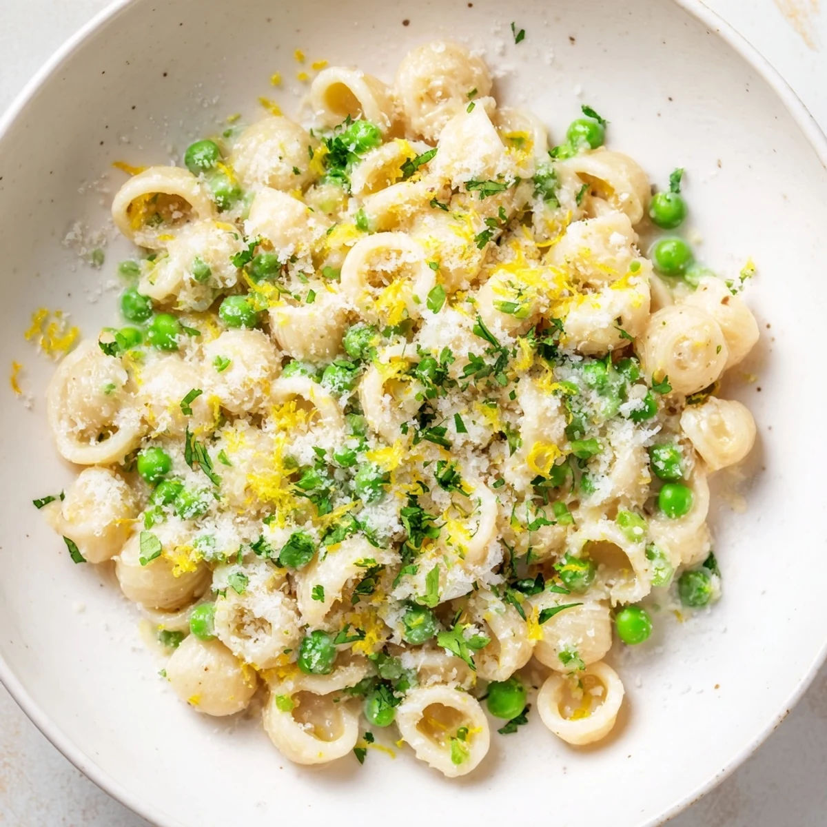 A close-up of steaming garlic butter ditalini, showing the peas and Parmesan cheese.
