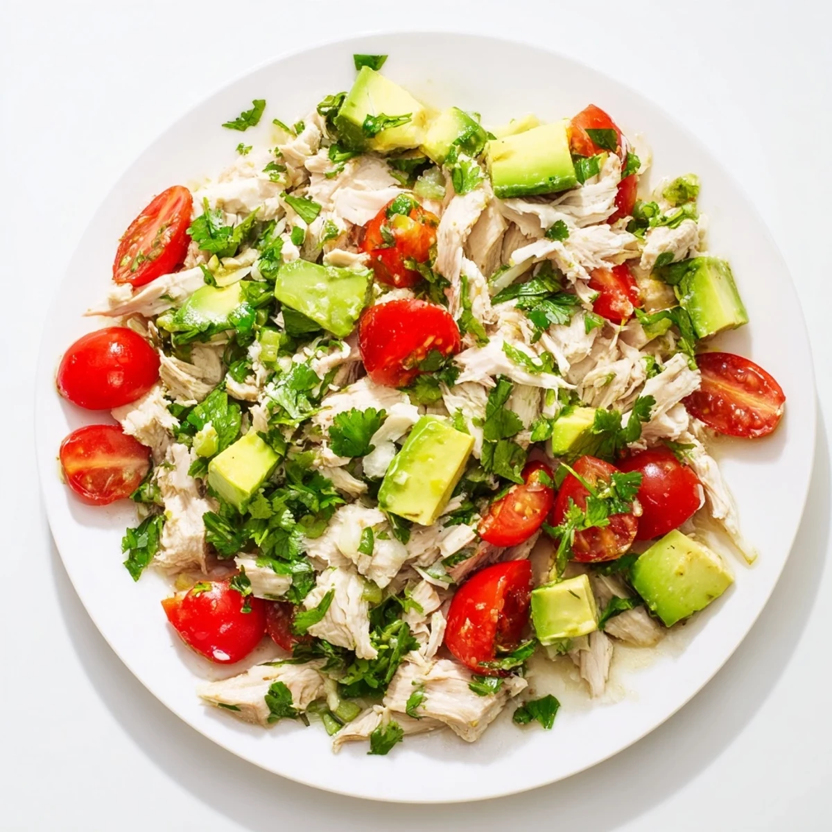 Avocado Chicken Salad mit zarten Hähnchenbruststücken, reifen Avocado-Stücken und knackigem Gemüse auf einem weißen Teller.