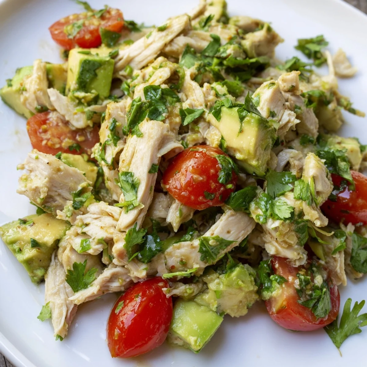 Eine cremige Avocado Chicken Salad mit glasigen Tomaten, roten Zwiebeln und grünen Gurkenwürfeln, fertig zum Servieren.
