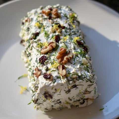 Elegant Winter Snowdrift Goat Cheese Log, richly coated in herbs and nuts, ready to serve with crackers.