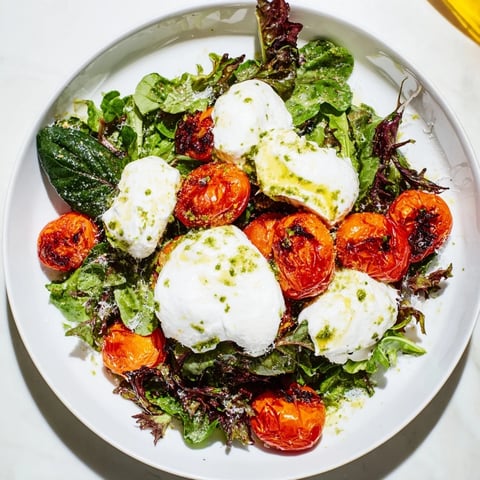Charred tomato salad with creamy burrata, featuring blistered tomatoes and fresh basil, ready to enjoy.