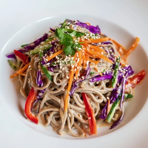 Cold soba noodle salad with vibrant vegetables, dressed in a creamy sesame-peanut sauce.