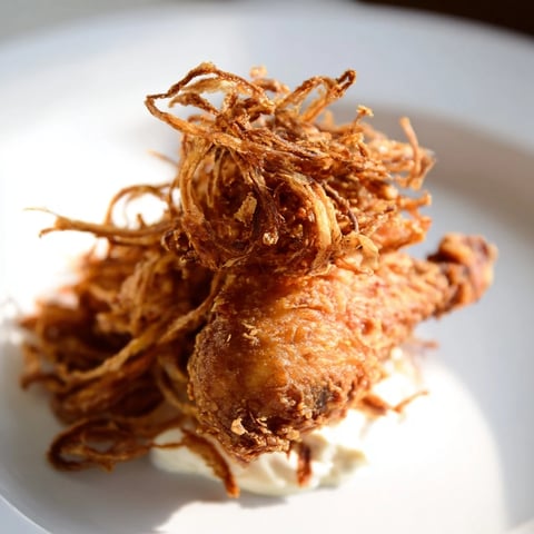 Golden-brown Crispy Onion Chicken Sandwich on a toasted brioche bun, layered with crispy fried onions and fresh lettuce.