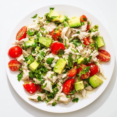 Avocado Chicken Salad mit zarten Hähnchenbruststücken, reifen Avocado-Stücken und knackigem Gemüse auf einem weißen Teller.