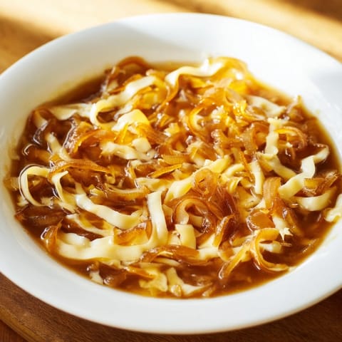 A steaming bowl of German Cheese and Onion Beer Soup, perfect for a cozy, flavorful dinner.
