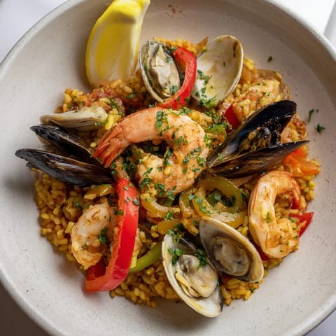 A close-up shot of steaming Spanish seafood paella, fragrant with saffron and herbs.