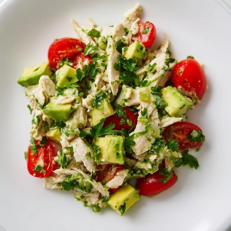 Frisch zubereitete Avocado Chicken Salad auf einer rustikalen Holzplatte mit Koriander, Limettenscheibe und Olivenöl.